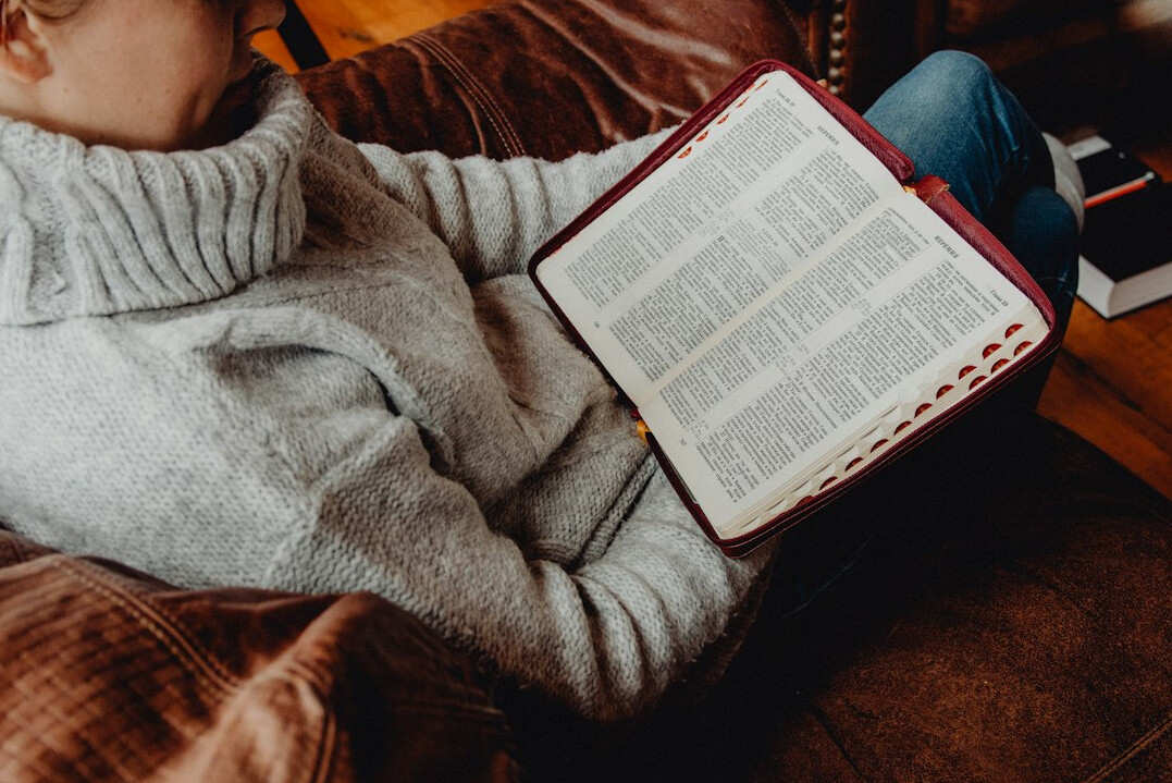 Woman reading a book thoughtfully on a sofa